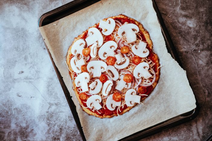 Bezlepková pizza před dopečením - Pizza před dopečením je plná cherry rajčátek, hub a rajčatové omáčky.