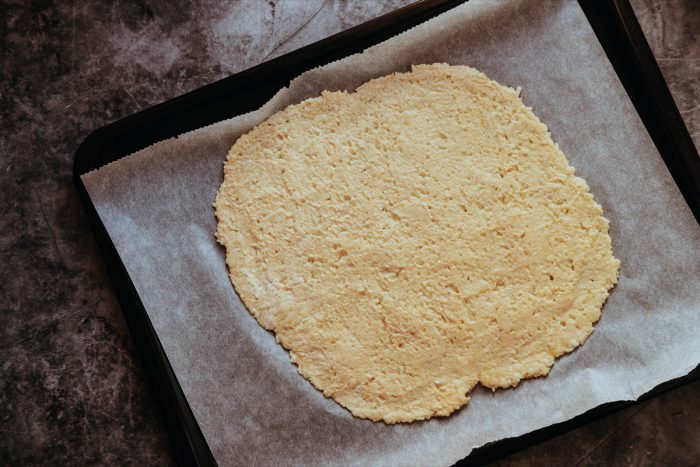 Těsto na zdravou pizzu - Těsto na zdravou pizzu nanesete na pečící papír a přidáte další ingredience.